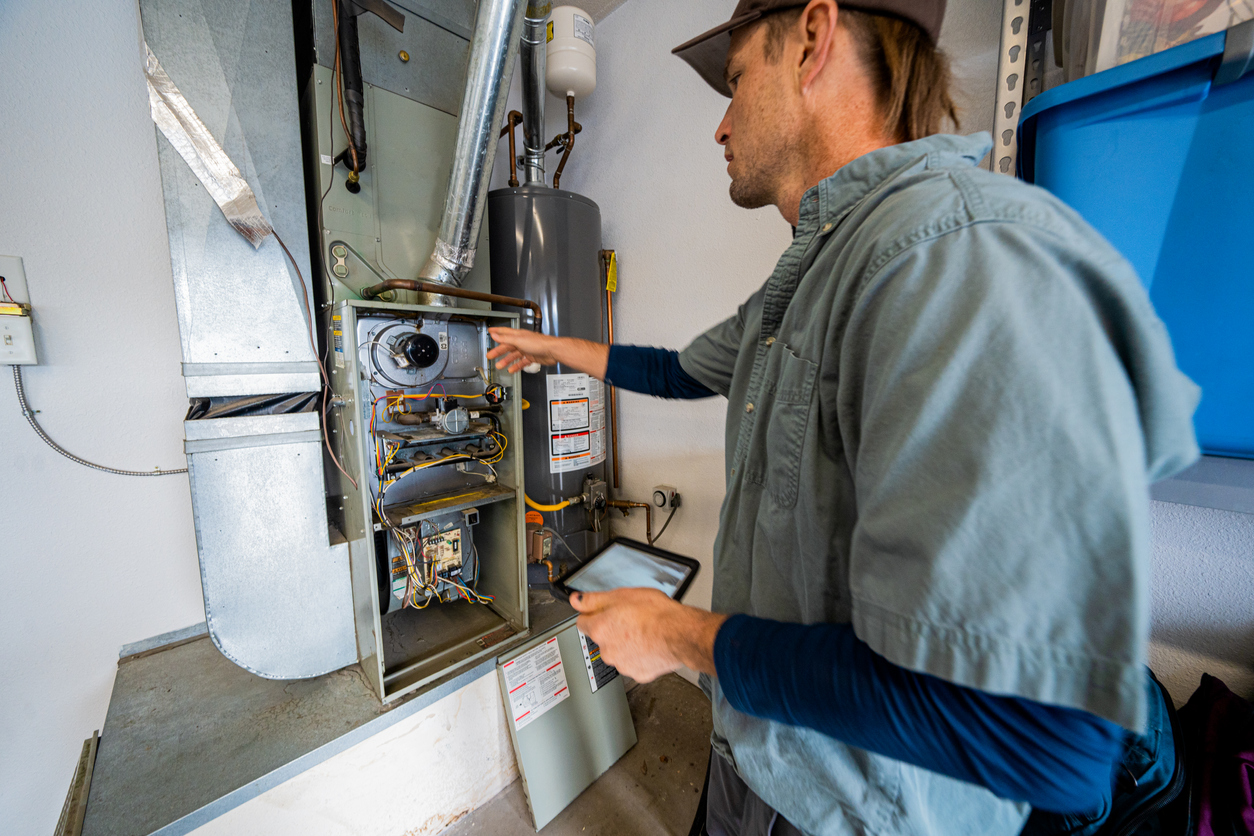 Furnace repair man working on basement furnace